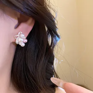 Gros plan détaillé montrant des boucles d'oreilles nœud en perles et zircons sur l'oreille