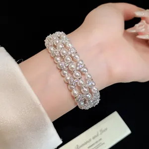 Elegant multi-strand pearl bracelet with zircon flower accents shown on woman's wrist
