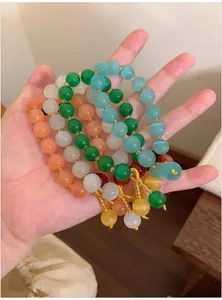 Detail of multi-color cat's eye stone beaded bracelets with dangling charms held in palm