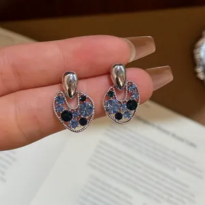 Detail of vintage silver stud earrings featuring blue crystals and a hollow irregular design.