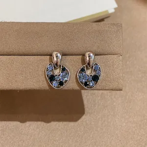 Retro hollow irregular stud earrings with blue and black crystals on display.