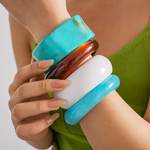 Dettaglio di bracciali spessi in resina multicolore con effetto marmo sul braccio