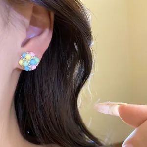 Vue rapprochée de boucles d'oreilles en perles colorées portées à l'oreille.