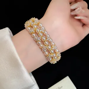 Detailed view of multi-layer pearl and rhinestone flower bracelet on wrist