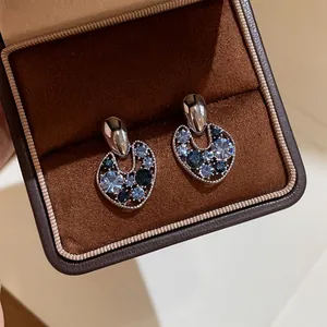 Close-up of elegant retro hollow earrings with blue crystals in a brown jewelry box