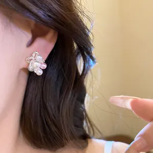 Gros plan sur des boucles d'oreilles nœud en perles et zircons portées par un modèle