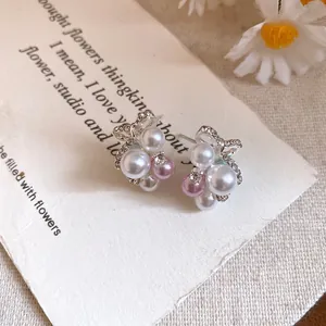 Gros plan de boucles d'oreilles nœud en perles et zircons sur un fond de papier rustique