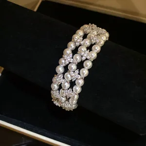Macro detail of vintage multi-layer pearl bracelet with flower zircon accents on stand.