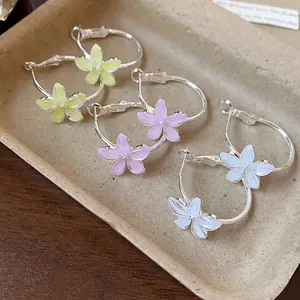 Close-up of elegant resin flower hoop earrings in yellow, pink, and white colors.