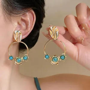 Detail shot of elegant French vintage gold hoop earrings featuring green floral accents
