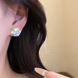 Gros plan détaillé d'une boucle d'oreille à tige en perles pastel multicolores sur l'oreille