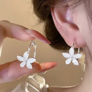 Detail shot of elegant white resin flower hoop earrings with silver needles for women