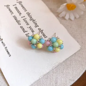 Vue macro de boucles d'oreilles clous en perles pastel colorées et zircons brillants