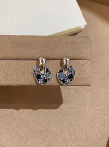 Detailed view of vintage hollow ear studs featuring sparkling blue and black crystals