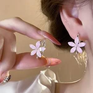 Elegant pink resin flower hoop earrings with shimmering details shown in close-up.