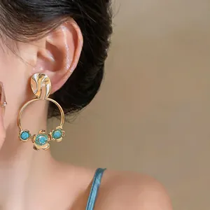 Detail view of French vintage gold hoop earrings with blue floral accents on a model's ear