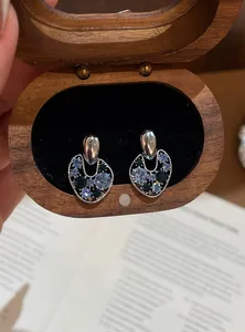Close-up detail of irregular hollow earrings featuring blue and green crystal inlays