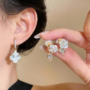 Close-up view of elegant floral and quatrefoil dangling earrings with crystals