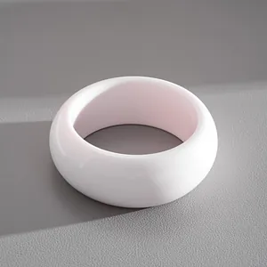 Primo piano di un bracciale rigido in resina bianca lucida dallo stile semplice.