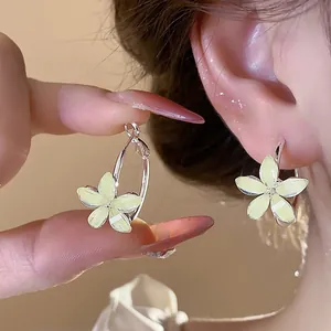 Close-up detail of elegant pale yellow resin flower hoop earrings worn on model's ear