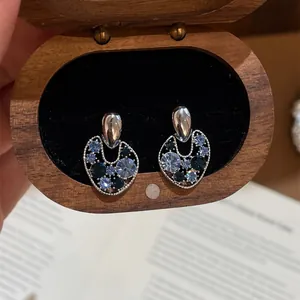 Close-up of vintage hollow stud earrings with blue crystals inside a wooden jewelry box
