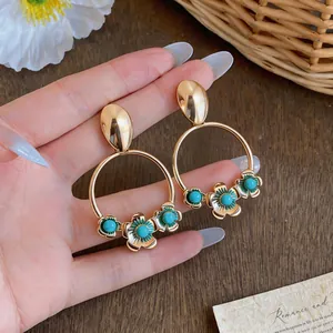 Detailed shot of vintage gold flower hoop earrings featuring turquoise-colored beads.