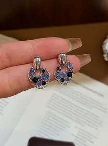 Macro view of vintage style hollow silver-toned stud earrings with blue sparkling crystals