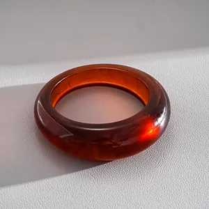 Primo piano di un bracciale in resina ambra con motivo marmorizzato su fondo ruvido.