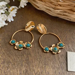 Detail of retro gold hoop earrings with turquoise acrylic flower accents.