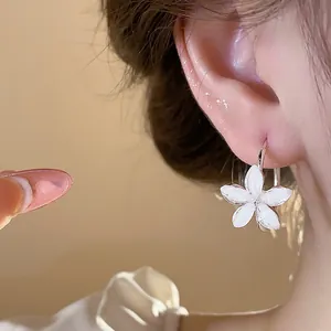 Detailed close-up showing elegant white resin flower hoop earring worn on an ear