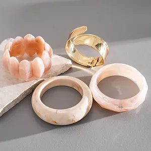 Detail view of acrylic marble and gold-tone metal bangles on stone prop