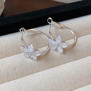 Detailed close-up showing the translucent resin flower design on silver hoop earrings
