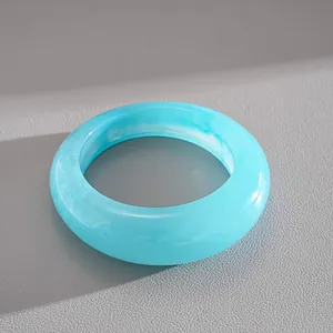 Dettaglio di un bracciale a cerchio in resina blu marmorizzata dal design minimalista