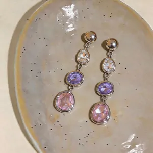 Detailed view of multi-colored teardrop and oval crystal earrings on a ceramic dish