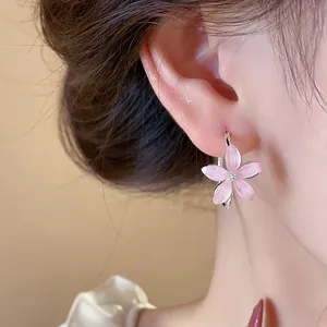 Close-up of elegant pink flower hoop earrings worn on an ear, featuring resin petals.