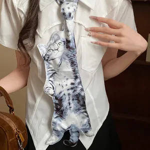 Vue détaillée d'un collier cravate imprimé chat exagéré porté sur une chemise blanche.