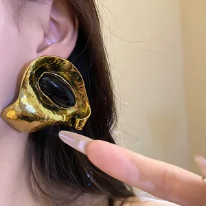 Gros plan sur une boucle d'oreille géométrique dorée avec un centre en résine noire