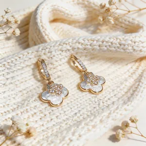 Detailed view of gold double four-leaf clover earrings with pearl texture and crystals.