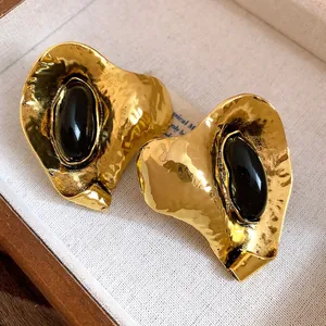 Détail de boucles d'oreilles vintage en or martelé avec de la résine noire élégante