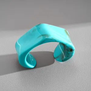 Dettaglio macro del bracciale rigido in resina marmorizzata turchese, stile minimal.