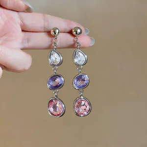 Detailed view of long teardrop earrings with multi-colored crystals in silver frames
