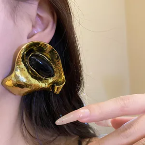 Gros plan détaillé d'une boucle d'oreille vintage dorée géométrique avec résine noire.