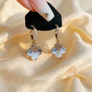 Elegant gold-plated hoop earrings with textured light blue clover dangles and crystals