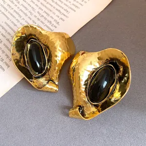 Gros plan de boucles d'oreilles vintage en or martelé et pierre en résine noire