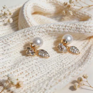 Detailed macro view of elegant rose and leaf earrings with white pearls and sparkling zircons