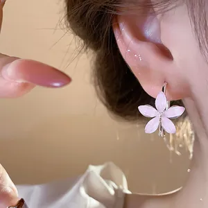 Close-up detail of minimalist pink resin flower hoop earrings on a model's ear