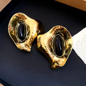Gros plan sur des boucles d'oreilles vintage en or martelé avec résine noire ovale.