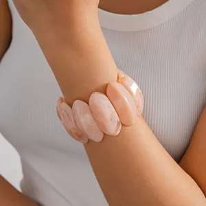 Detailed view of a stylish pink marbled acrylic geometric chunky bracelet on a female wrist.
