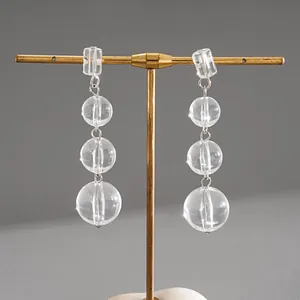 Détail de boucles d'oreilles pendantes en perles de cristal transparent sur support doré.