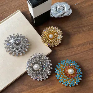 Gros plan de broches fleur plaquées or 18 carats avec zircons et perles fines.